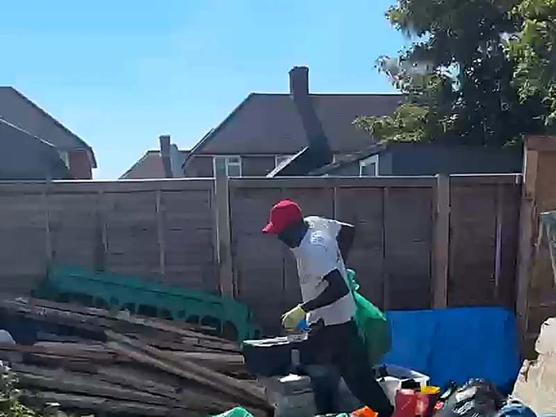A gardener bagging green waste on a cleared garden plot