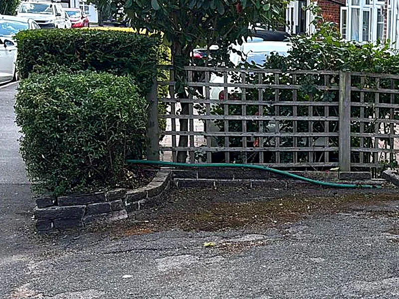 A clipped hedge, trellis and setted edge in a tidy front garden